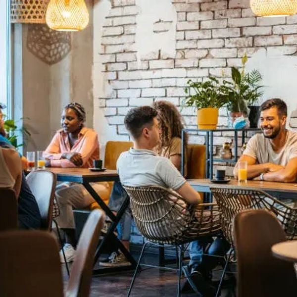 People chatting and enjoying drinks in a cozy café with rustic decor.