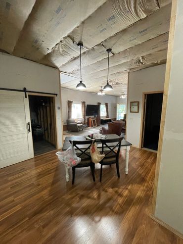 Dining area with hanging lights and unfinished ceiling.