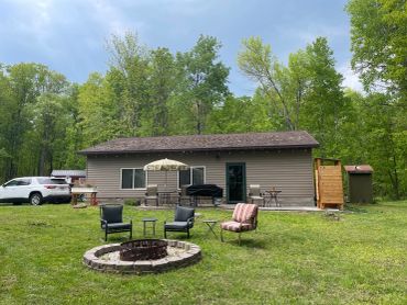 Backyard with fire pit and seating in front of a small house.