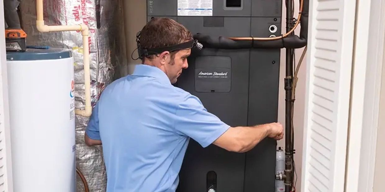 Technician finishing installation of a HVAC system in a utility closet.