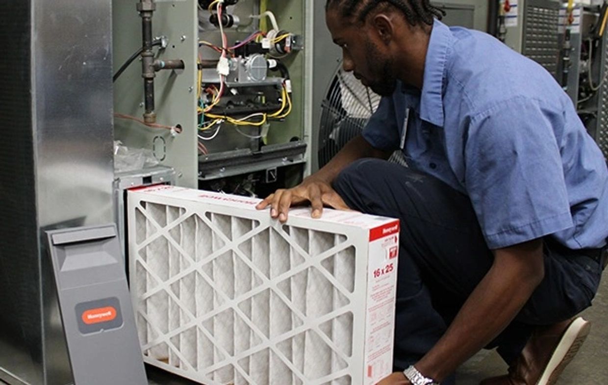 Technician replacing an air filter in an HVAC system.