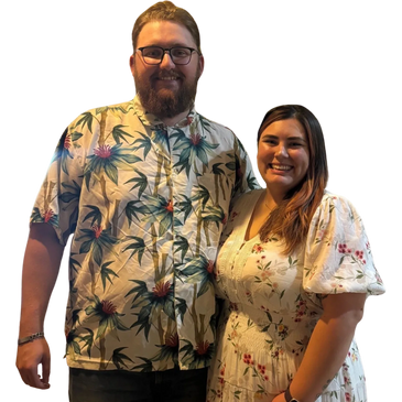 A smiling couple dressed in floral outfits posing together.
