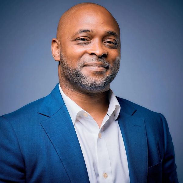 A middle-age black man in a blue blazer and white dress shirt. 