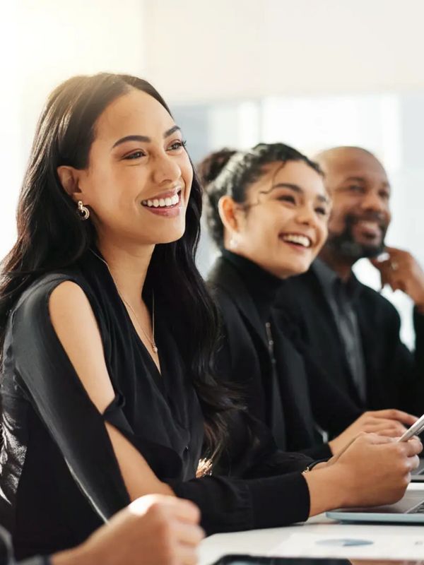 People in a meeting with laptops open and smiling towards the right. 