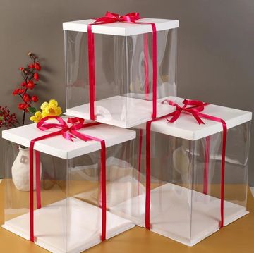 Three clear cake boxes with cake bases stacked in a pyramid with red ribbon