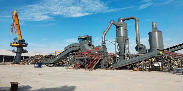 Industrial machinery setup with conveyor belts and a tall yellow crane under a blue sky.