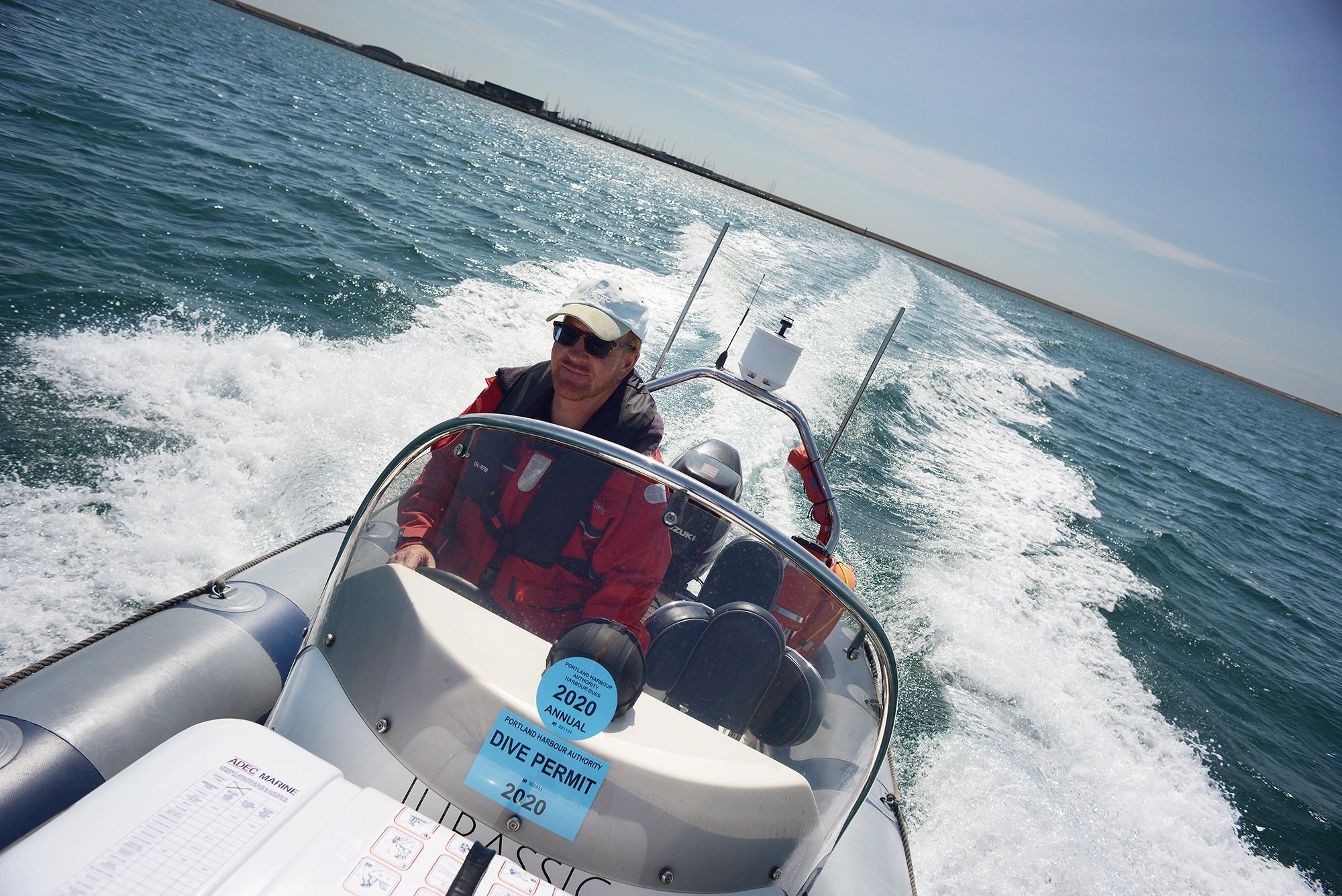 Person driving a RIB at speed across Portland Harbour