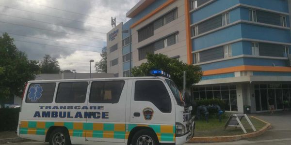 Ambulance parked outside a modern hospital building on a cloudy day.