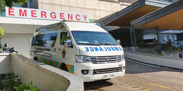 An ambulance parked outside a hospital emergency entrance during the day.