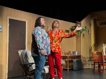 Two actors performing on stage in colorful costumes.