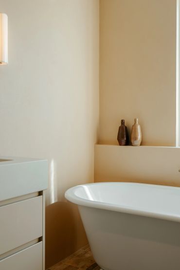 Minimalist bathroom with a white freestanding bathtub and two decorative bottles.