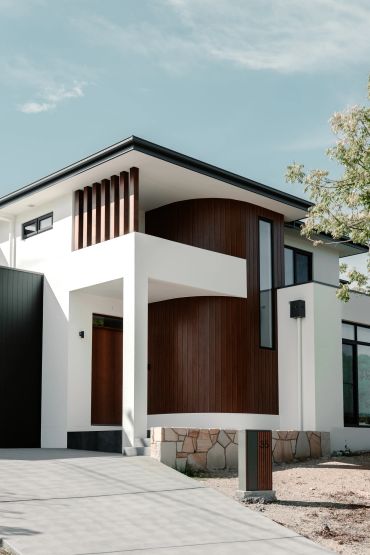 Modern house with white and wood exterior under a clear sky.