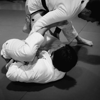 Two martial artists sparring in Brazilian Jiu-Jitsu on a mat.