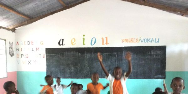 Excited kids reach up into the air and jump in their new classroom