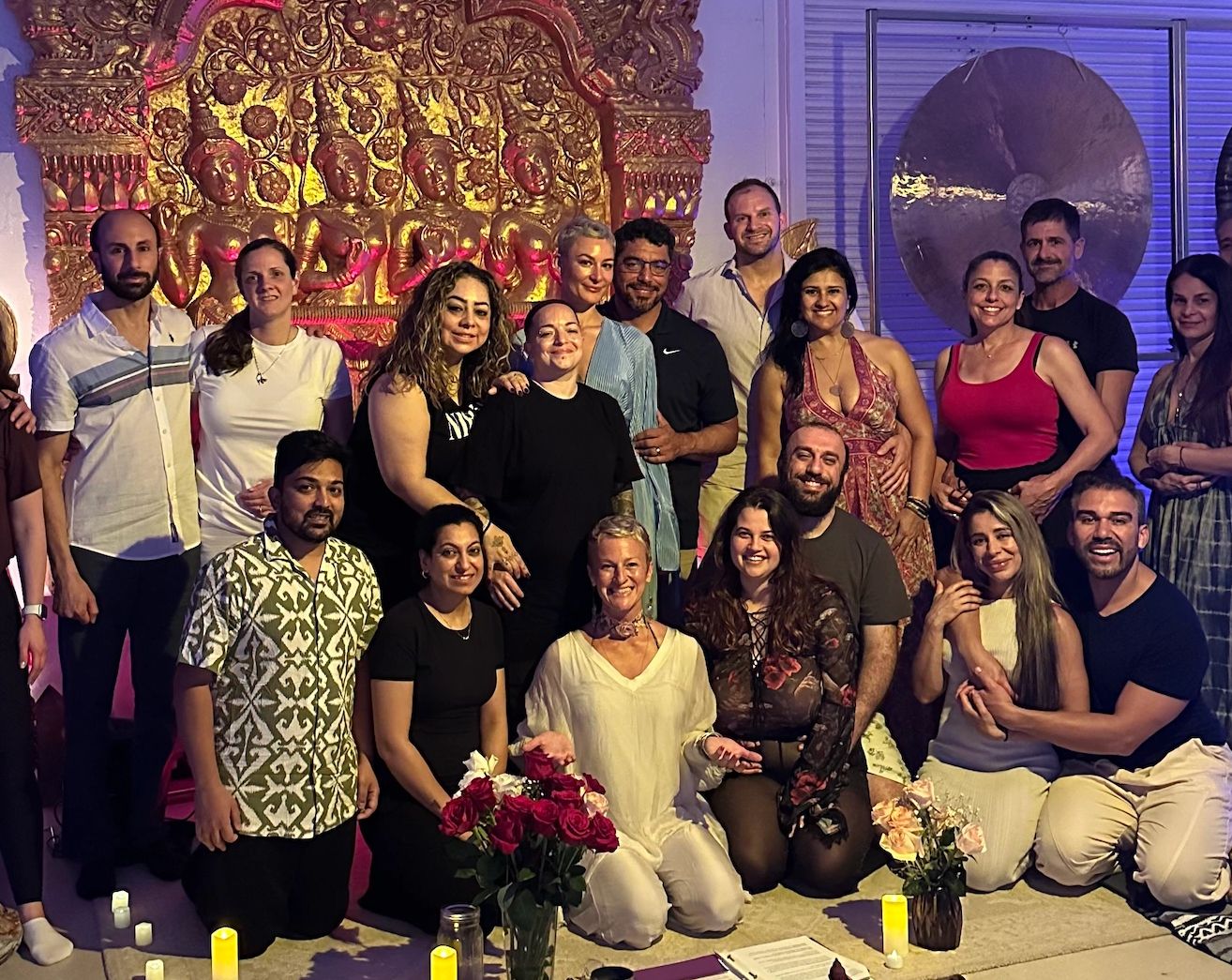 Group of people posing together in a decorated room with candles and flowers.