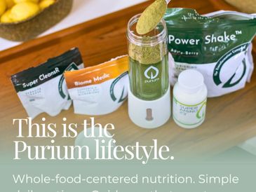 Purium health supplements and blender setup on a wooden surface.