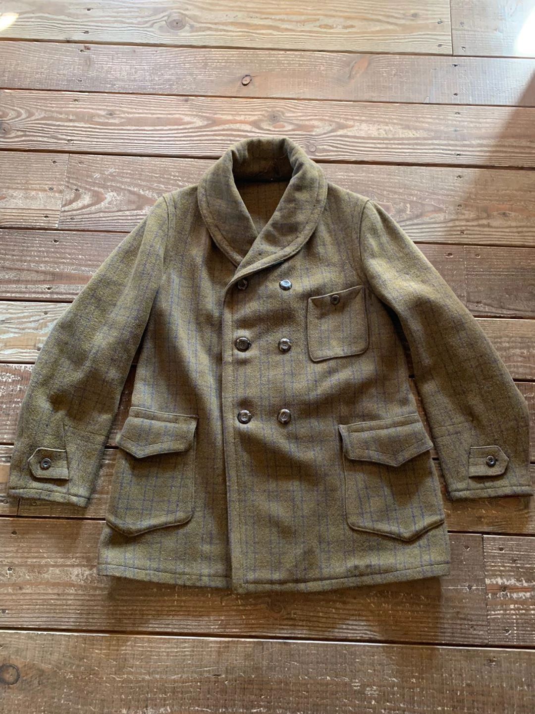 Brown plaid double-breasted wool jacket on wooden floor.