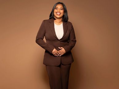 Smiling woman in a brown suit against a brown background.