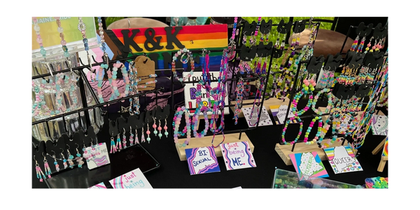 Colorful handmade beaded jewelry with LGBTQ+ pride signs on display.