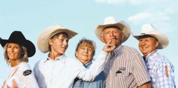 Group of people in cowboy hats posing outdoors.
