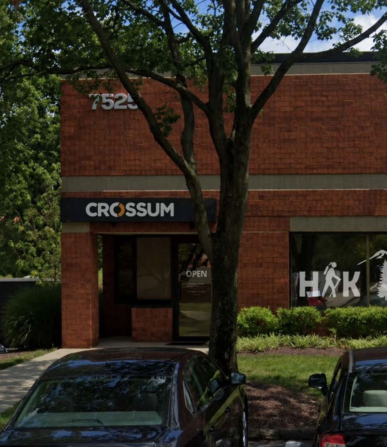 Brick building with Crosssum sign and parked cars in front.