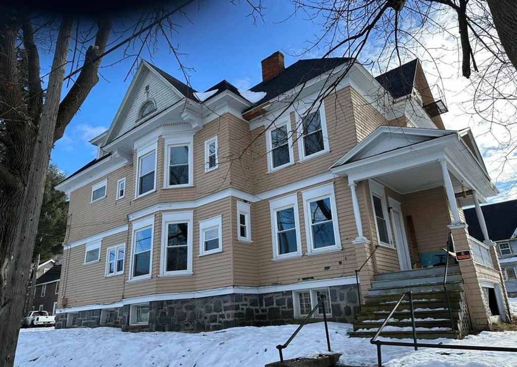 Large beige house with white trim on a snowy day.