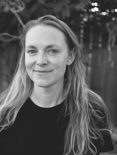 Black and white portrait of a woman with long hair smiling gently outdoors.