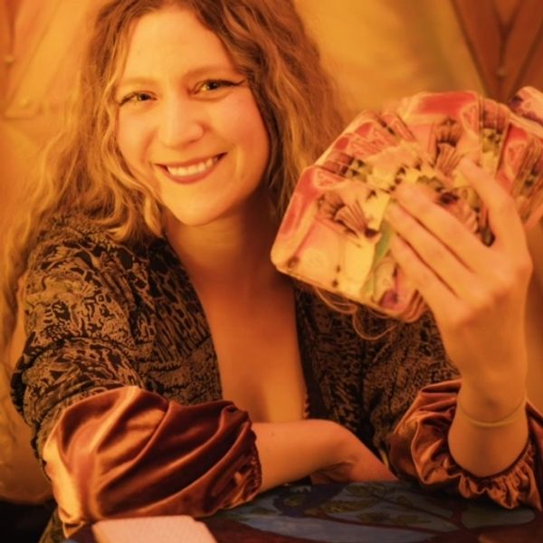 Tarot reader holding up tarot cards in one hand and smiling