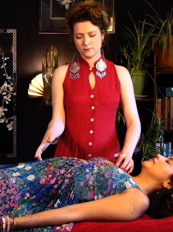 Reiki Master performing in-person healing session on woman