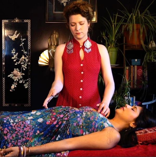 Reiki Master performing in-person healing session on woman
