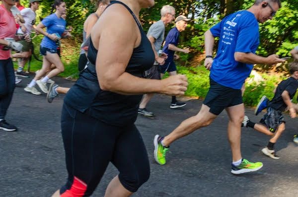 Group of people running outdoors in various athletic wear.