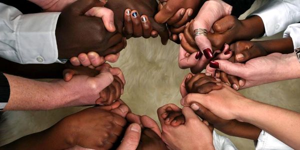 Diverse hands joined in a circle symbolizing unity and support.