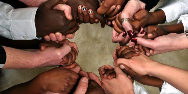 Diverse hands joined in a circle symbolizing unity and support.