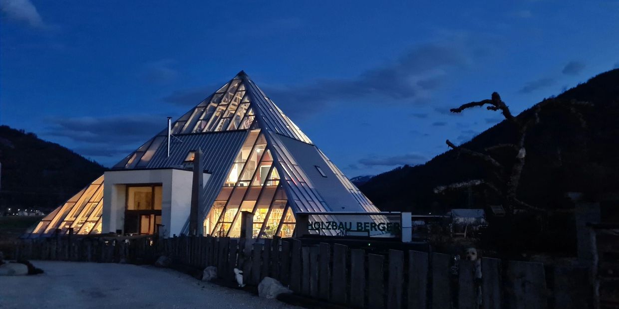 Pyramidenförmiges Gebäude bei Nacht beleuchtet.