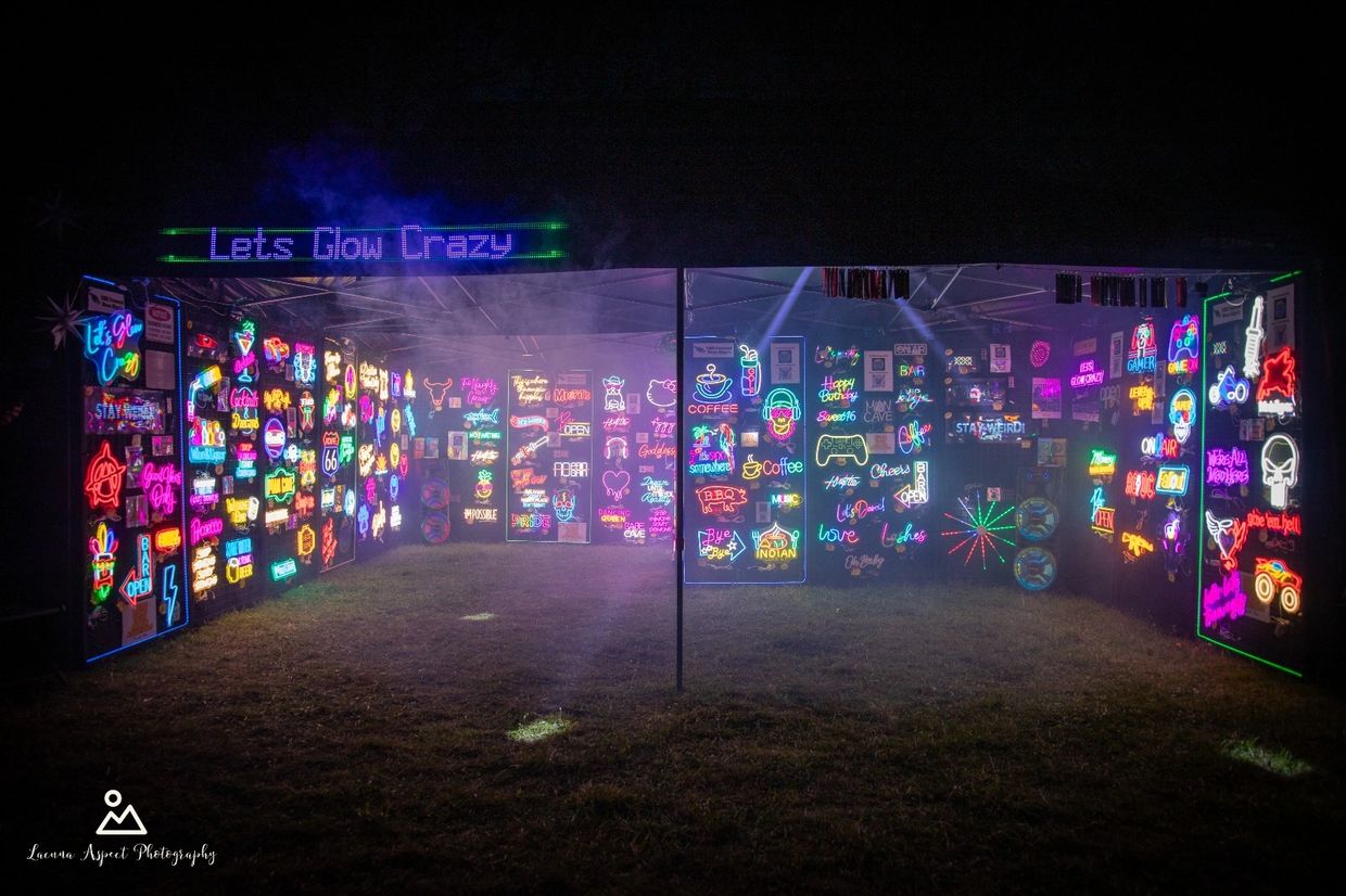 A vibrant neon sign display booth glowing in the dark with the title 'Lets Glow Crazy'.