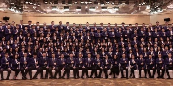 Large group of formally dressed people posing for a group photo indoors.