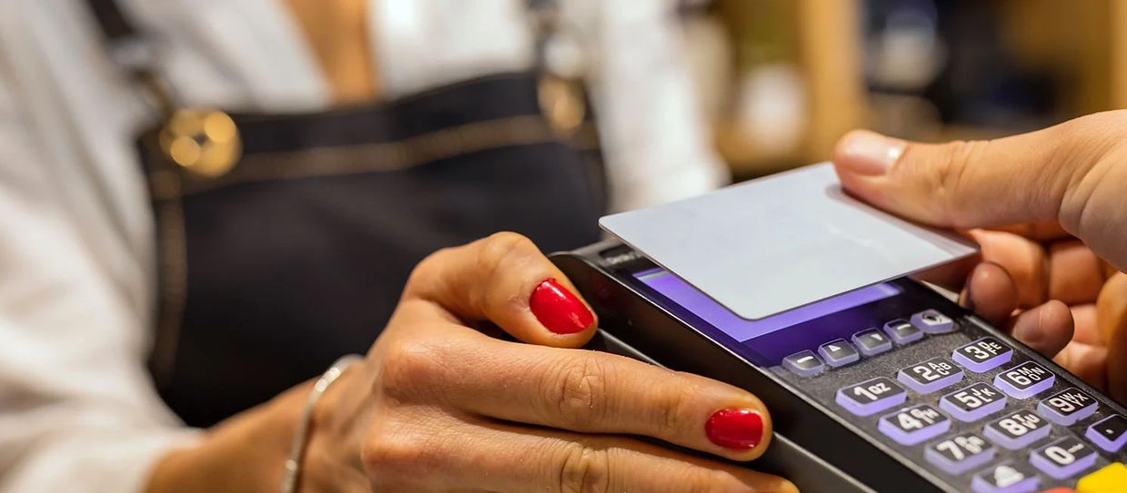 Person making a contactless payment with a card on a payment terminal.