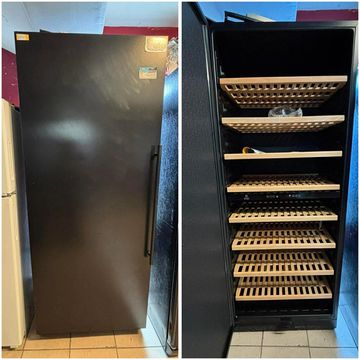 Tall black wine refrigerator with multiple wooden shelves for wine storage.