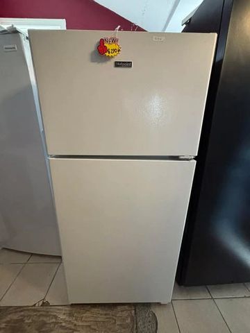 A white refrigerator with a 'New' price tag on the freezer door.