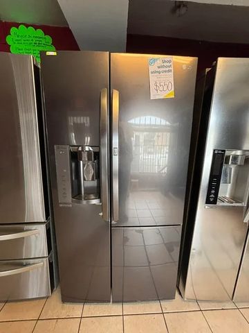 Stainless steel side-by-side refrigerator with water dispenser in a store.