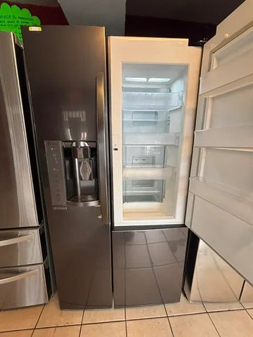 Modern side-by-side refrigerator with open freezer door and water dispenser.