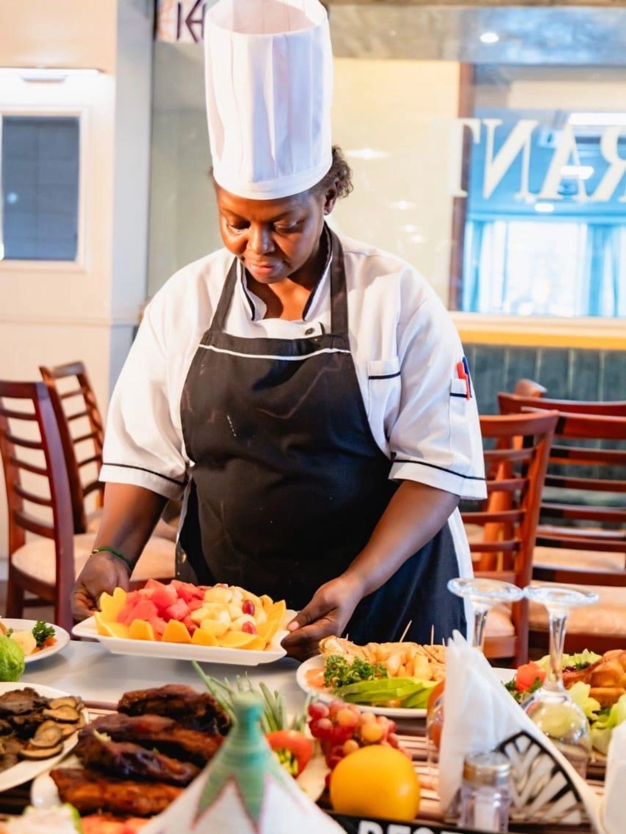 Chef presenting a colorful fruit platter in a restaurant setting.
