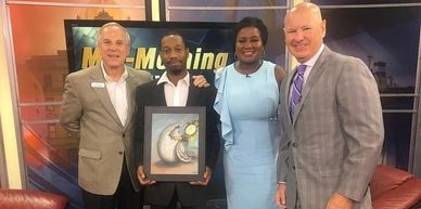 Four people posing with an award on a TV show set.