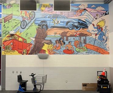 Colorful cartoon mural with characters, a car, eagle, and beach scene in a room.