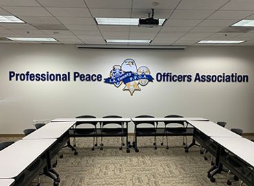 Conference room with 'Professional Peace Officers Association' sign and chairs around tables.