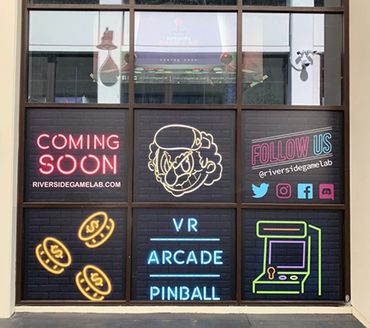 Neon signs announcing a new VR arcade and pinball venue coming soon.