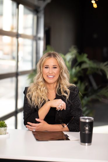 Woman smiling at desk in modern office space.
