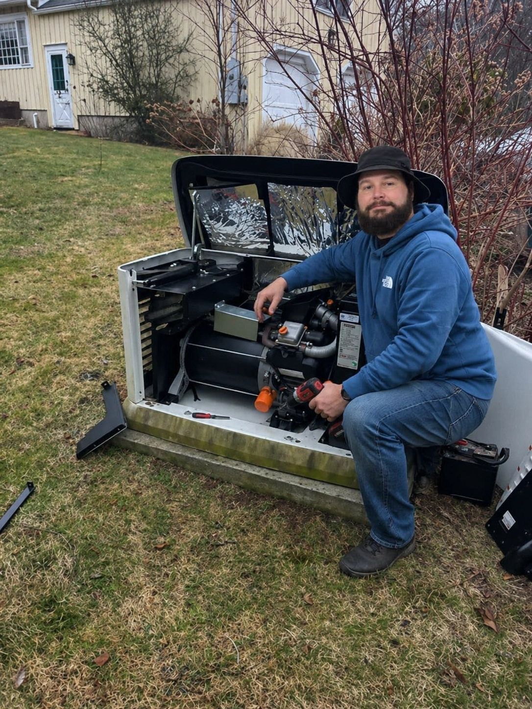 Man in blue hoodie working on an outdoor generator.