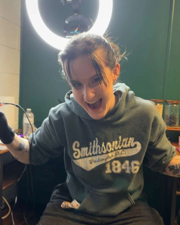 A joyful person wearing a Smithsonian hoodie with a ring light behind them.