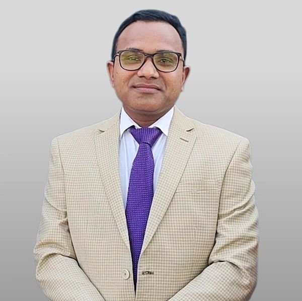 Man in beige suit with purple tie and glasses against gray background.